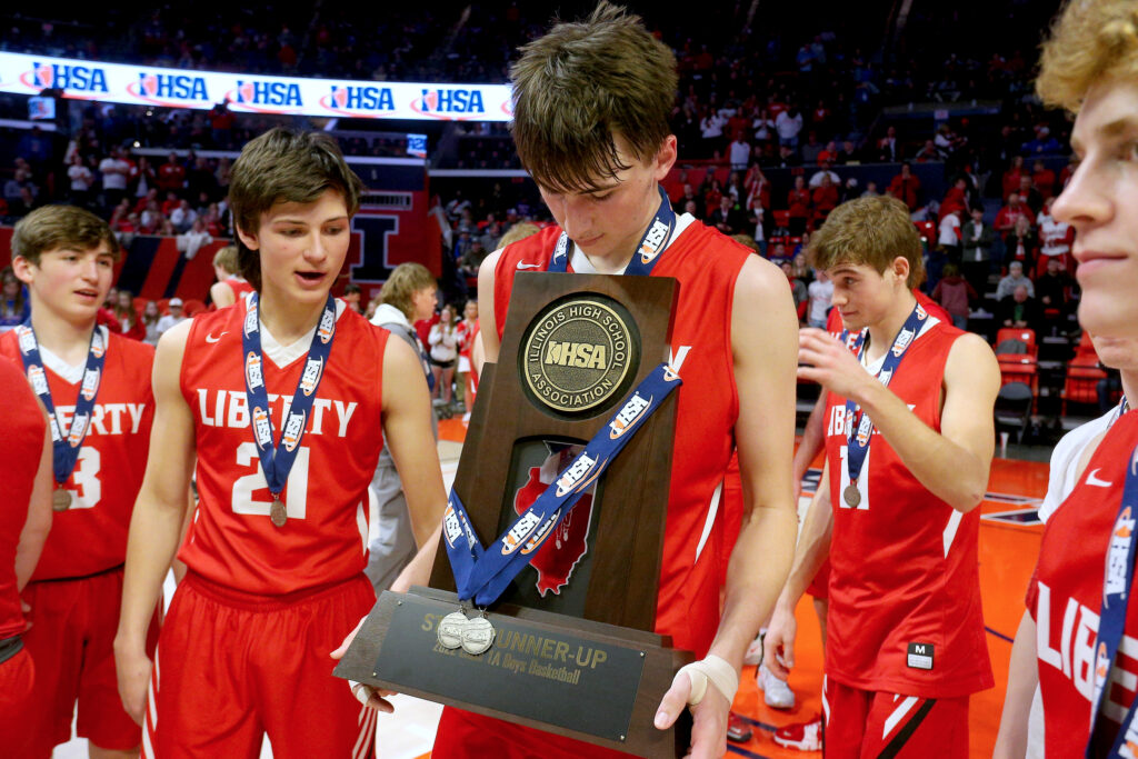 March 12, 2022 - Champaign, Illinois - Liberty's Logan Robbins carries the team's second place trophy after their Class 1A state championship basketball game against Yorkville Christian. The Eagles fell to the Mustangs, 54-41.   (Photo: PhotoNews Media/Clark Brooks)
