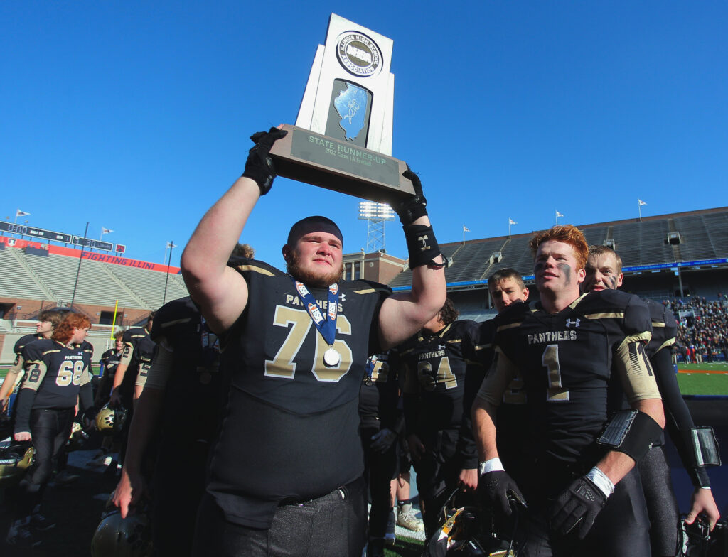 November 25, 2022 - Champaign, Illinois - Standing next to Ross Riley, Camp Point's Cole Pracht holds up the team's runner-up trophy after the Class 1A title game on Friday. The Panthers fell to Lena-Winslow, 30-8.   (Photo: PhotoNews Media/Clark Brooks)