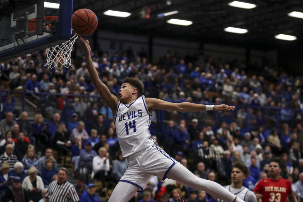 Quincy’s Dom Clay (14) lays the ball in off the glass during the Blue Devils game against the Rock Island Rocks Friday in Quincy.  Mathew Kirby/Herald Whig-Courier Post