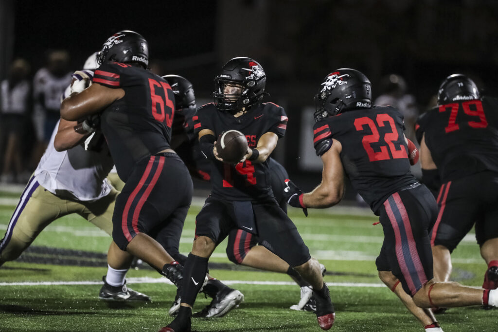 Hannibal’s Waylon Anders (14) hands the ball off to Aneyas Williams (22) during the Pirates game against the Troy Trojans, Friday in Hannibal.  Mathew Kirby (Herald WhigCourier Post)