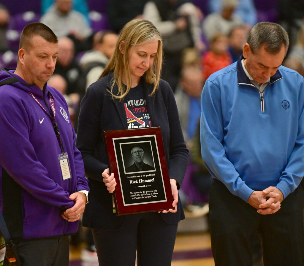 Christy Noland, daughter of former St. Louis Post-Dispatch sportswriter Rick Hummel, is flanked by Collinsville Athletic Director Clay Smith and former athletic director Bob Bone during a moment of silence before the Quincy vs Althoff quarterfinal game at the Collinsville Prairie Farms Holiday Classic at Collinsville High School on Thursday December 28, 2023. Hummel, originally from Quincy, died after retiring from the Post-Dispatch at age 77 in 2023.
Photo by Tim Vizer for Muddy River Sports