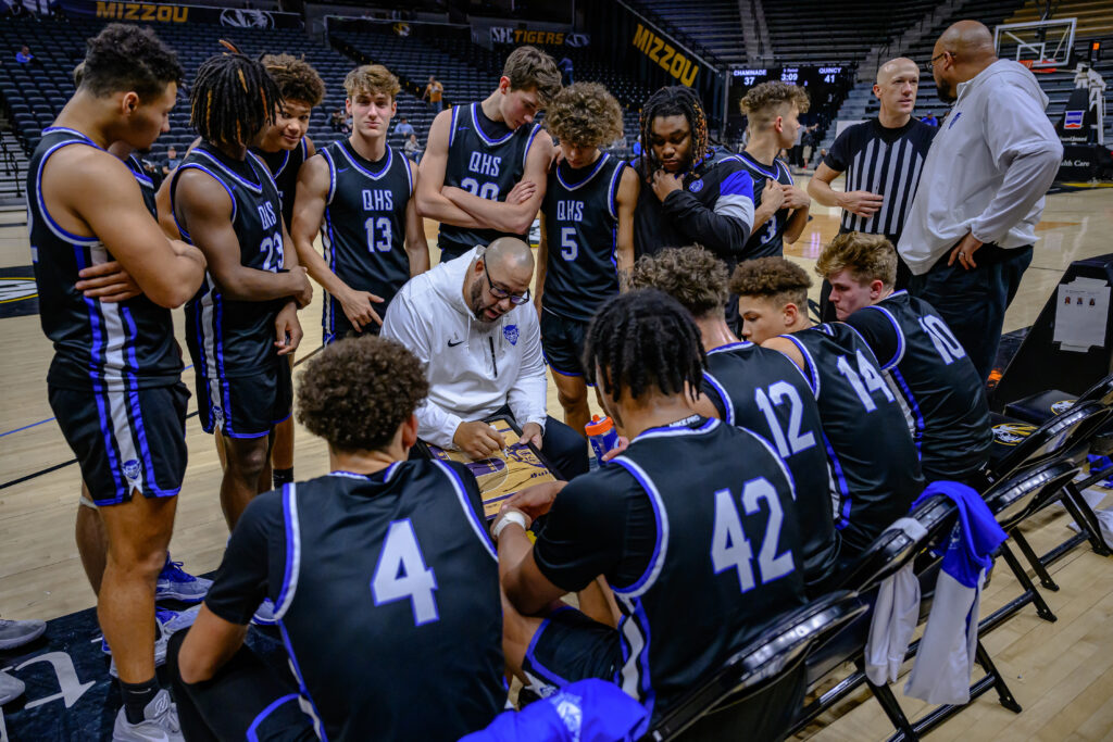 Quincy Notre Dame's head coach Andy Douglas works strategy with his team during a time out