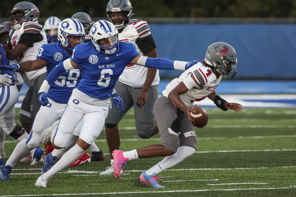 Quincy’s Ben Schelp (6) pressures the quarterback during the Blue Devils game against the Alton Redbirds, Friday in Quincy.  Mathew Kirby (Herald WhigCourier Post)